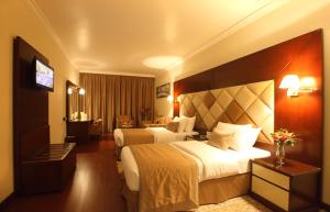 a hotel room with two beds and a television at Gulf Inn Hotel Deira Formerly City Star Hotel in Dubai