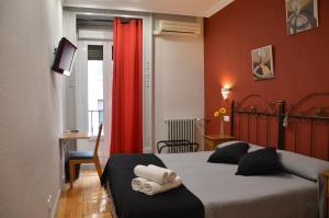 a bedroom with two beds and a red curtain at Hostal Aresol in Madrid