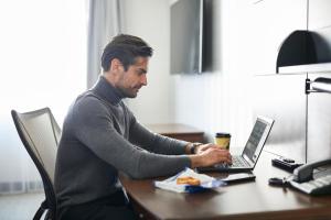 un homme assis à un bureau en utilisant un ordinateur portable dans l'établissement Club Quarters Hotel Embarcadero, San Francisco, à San Francisco