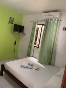 1 dormitorio con 1 cama con cortinas verdes y ventana en Pousada Malu, en Fortaleza