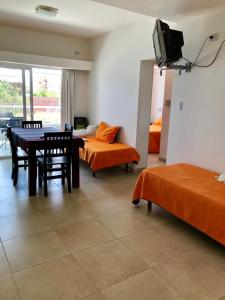 a room with a table and chairs and a tv at Departamentos LG in Las Grutas