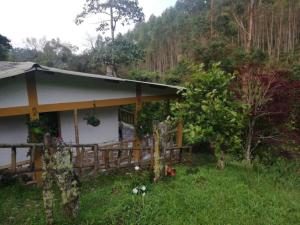 a house with a wooden fence in a field at Eco-Cabaña Termales Santa Rosa in Santa Rosa de Cabal