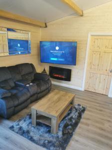 a living room with a couch and a table and a tv at The Lodge Mountain View Log Cabin , Attymass Ballina in Boyhollagh
