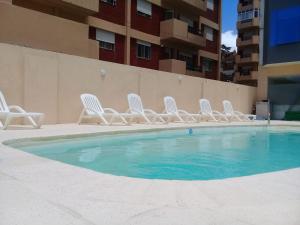 a group of white chairs sitting around a swimming pool at Hotel SKY in San Bernardo
