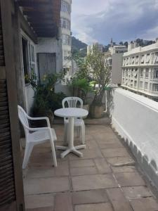 - Balcón con mesa blanca y 2 sillas en Apartamentos Copacabana ampla vista mar, en Río de Janeiro