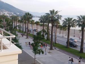um grupo de pessoas andando por uma rua com palmeiras em DREAM APARTMENT Vlore em Vlorë