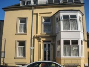 a yellow house with a car parked in front of it at 2 berth first floor flat Apsley 4 in Great Yarmouth