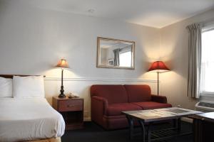 a hotel room with a bed and a red chair at Alpine Inn & Suites Rockford in Rockford