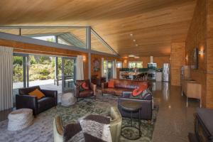 a living room with leather furniture and a kitchen at Hydrangea Cottages in Punakaiki