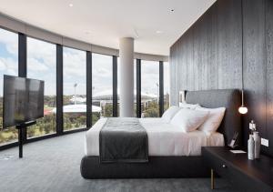 een slaapkamer met een groot bed en een groot raam bij Eos by SkyCity in Adelaide