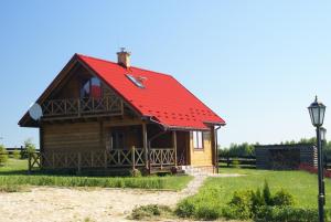 a small wooden house with a red roof at Domy nad jeziorem Blanki in Lidzbark Warmiński