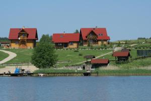 um par de grandes casas de madeira ao lado de um lago em Domy nad jeziorem Blanki em Lidzbark Warmiński