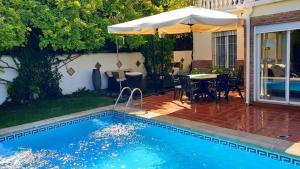 a swimming pool with a table and an umbrella at Villa Albaida in La Zubia