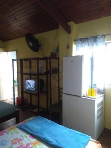 uma cozinha com frigorífico e uma televisão em Suíte Aconchegante em Caraguatatuba