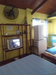 um quarto com uma cama e uma televisão num quarto em Suíte Aconchegante em Caraguatatuba