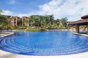 a large swimming pool at a resort with palm trees at Ocean View Condo in Los Sueños in Herradura