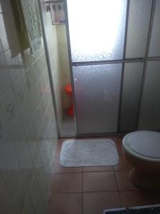 uma casa de banho com um chuveiro, um WC e um tapete em Suíte Aconchegante em Caraguatatuba