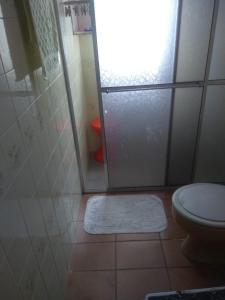 a bathroom with a shower with a toilet and a rug at Suíte Aconchegante in Caraguatatuba +3 photos