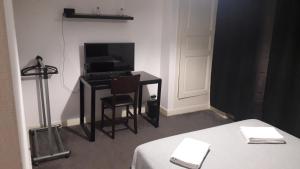 Cette chambre comprend un bureau avec une télévision et une table avec une chaise. dans l'établissement Chambres d'Hotes Centre Ville, à Agen