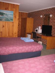 Cette chambre comprend deux lits et un bureau avec un ordinateur. dans l'établissement Orbost Country Road Motor Inn, à Orbost