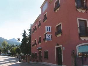 un edificio rojo con un reloj a un lado en Hostal Rural La Montería, en Orcera