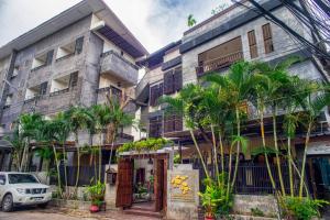 a building with palm trees in front of it at Ban Kong Rao Guesthouse in Chiang Mai