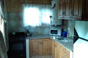 una cucina con armadi in legno, lavandino e forno a microonde di Cabaña El Sueño de La Abuela a El Hoyo