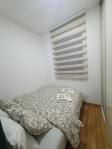 Cama en habitación con almohada y ventana en Pinevile apartman 4, en Zlatibor