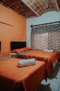 2 camas en una habitación con paredes de color naranja en Bungalows Flamingos, en Rincón de Guayabitos