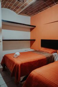 Habitación con 2 camas y paredes de color naranja. en Bungalows Flamingos en Rincón de Guayabitos