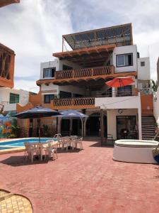a building with tables and umbrellas next to a pool at Bungalows Flamingos in Rincon de Guayabitos