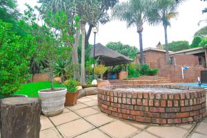 una fuente de ladrillo en un patio con árboles y una casa en Upmarket Villa with pool & lush garden en Pretoria