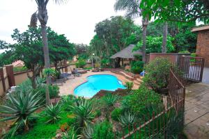 Upmarket Villa with pool & lush garden في بريتوريا: حديقة خلفية بها مسبح وشرفة