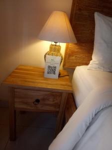 a bedside table with a lamp and a sign on it at Umah Dajane Guest House in Ubud