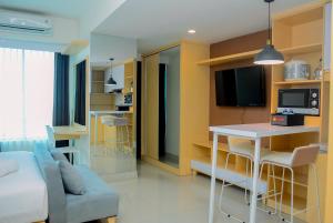 a kitchen and living room with a couch and a table at Grand Kamala Lagoon Studio Apartment with Modern Interior By Travelio in Pekayon Satu