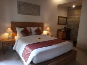 a bedroom with a large white bed with two lamps at Umah Dajane Guest House in Ubud