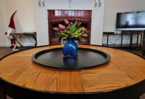 Un jarrón azul con flores rosas sobre una mesa. en McKenzie House, en Healesville