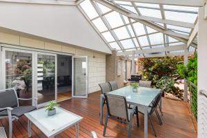 a conservatory with a table and chairs on a deck at Frewville 7A Apartment in Mount Gambier