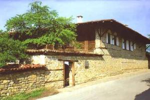 un vieux bâtiment en pierre avec un arbre en face de lui dans l'établissement Ambaritsa Hotel, à Gorna Oryahovitsa