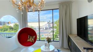 a living room with a red chair and a large window at Kunst in Bangkok