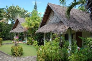 una casa con techo de hierba y patio en Marcosas Cottages Resort en Moalboal