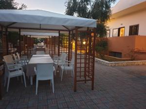 un restaurante con mesas y sillas bajo una sombrilla blanca en Hotel Palme Gemelle en Vieste
