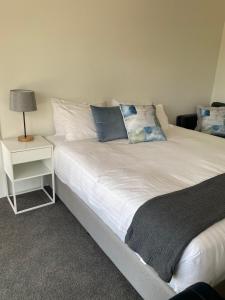 
a hotel room with a bed, chair, and nightstand at Orford Blue Waters Hotel in Orford
