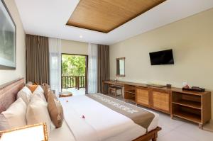 a bedroom with a bed and a desk and a television at Radha Phala Resort & Spa in Ubud