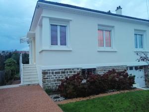 a white house with a brick wall and windows at Chez Papinette, proche gare et centre, pdj compris in Niort