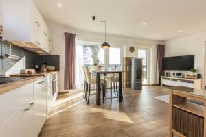 a kitchen with white cabinets and a table with chairs at 5 Sterne Ferienhaus direkt am See mit Sauna-Kamin-Garten in Krakow am See