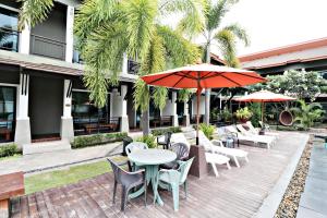 um pátio exterior com mesas, cadeiras e guarda-sóis em P' Private Resort Cha Am em Cha Am