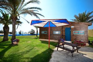 a small cabin with a bench and an umbrella at Dor al Hayam in Dor