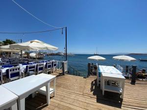 a wooden deck with tables and umbrellas on the water at Manolya Hotel in Bodrum City