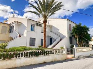 a white house with a palm tree in front of it at Seaview and sun all day long in Los Pinos, Almuñecar, Andalusia in Almuñécar